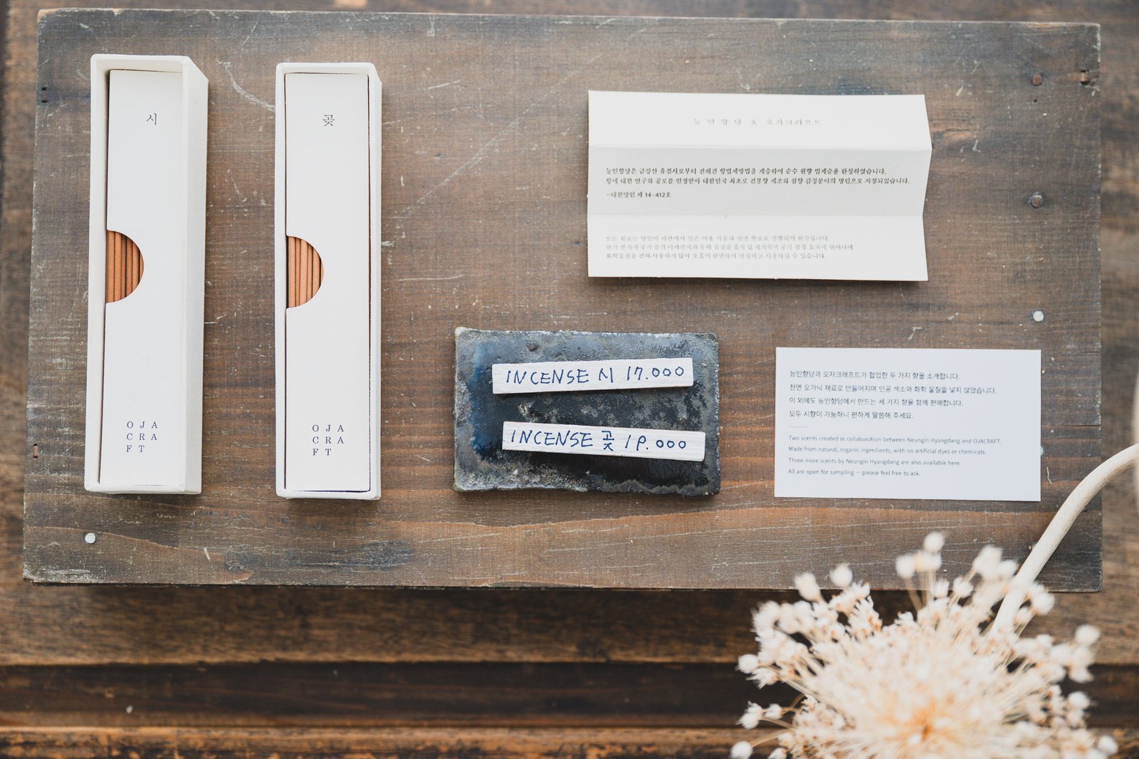 OJA CRAFT-branded incense sticks in white boxes labeled "시" and "곶," next to a bilingual Korean-English collaboration card and a dark ceramic incense holder