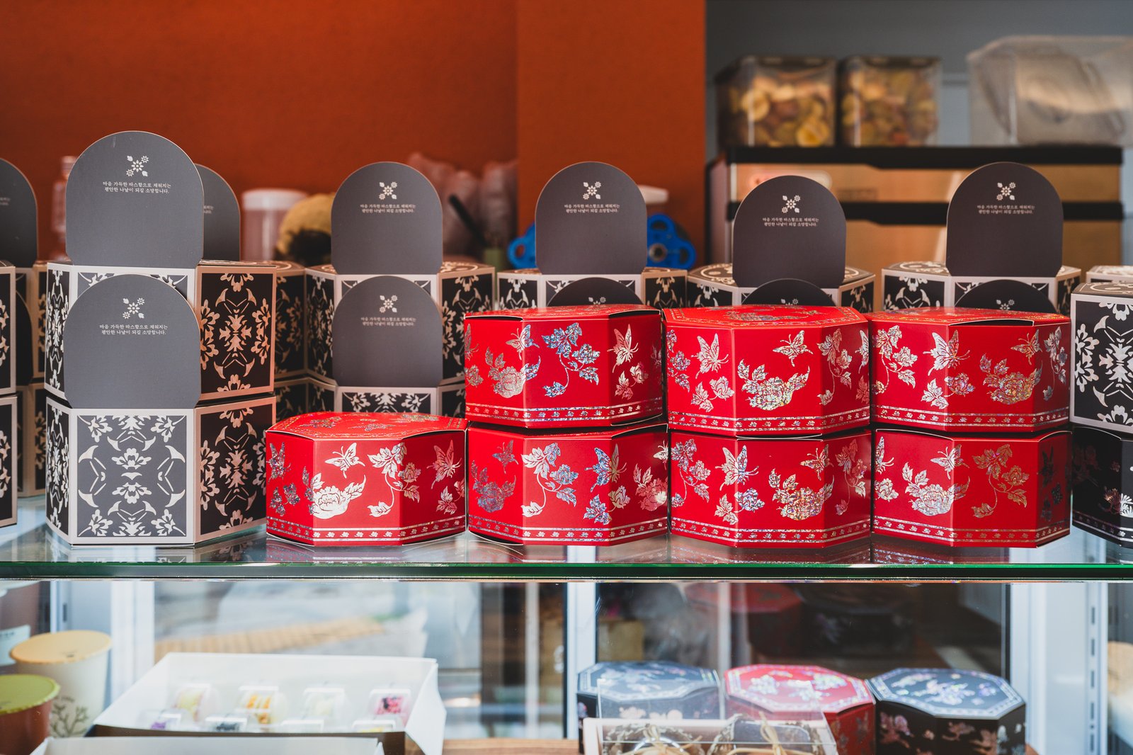 Octagonal tin gift boxes on display, in red and black with butterfly and floral patterns