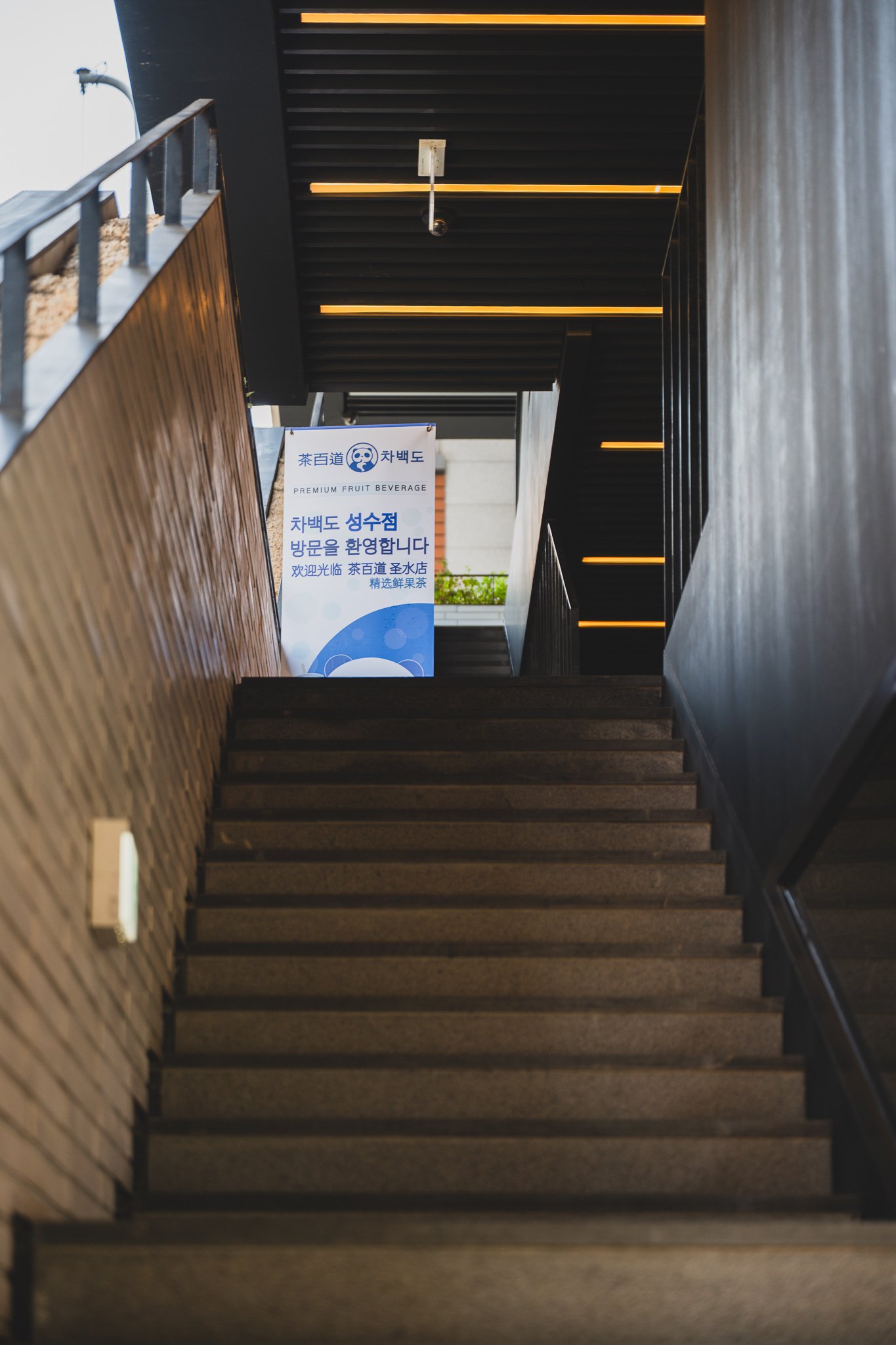 Staircase leading to the second floor, with a welcome banner reading "Welcome to Chabaidao Seongsu" in Korean and Chinese