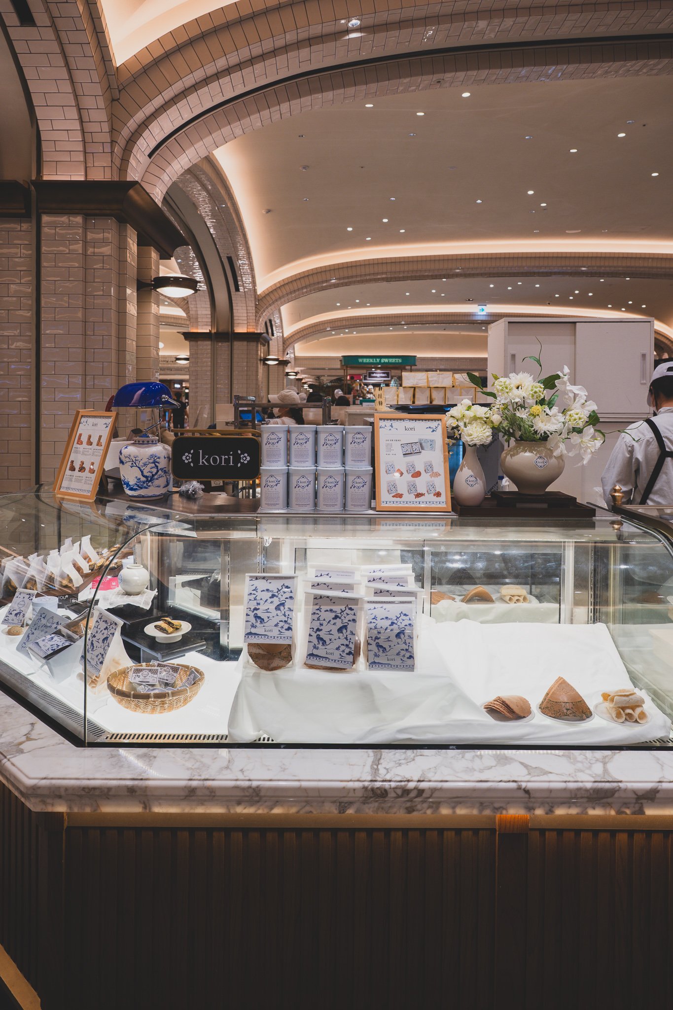 Kori's counter display inside Sweet Park, with a white porcelain jar and blue lamp