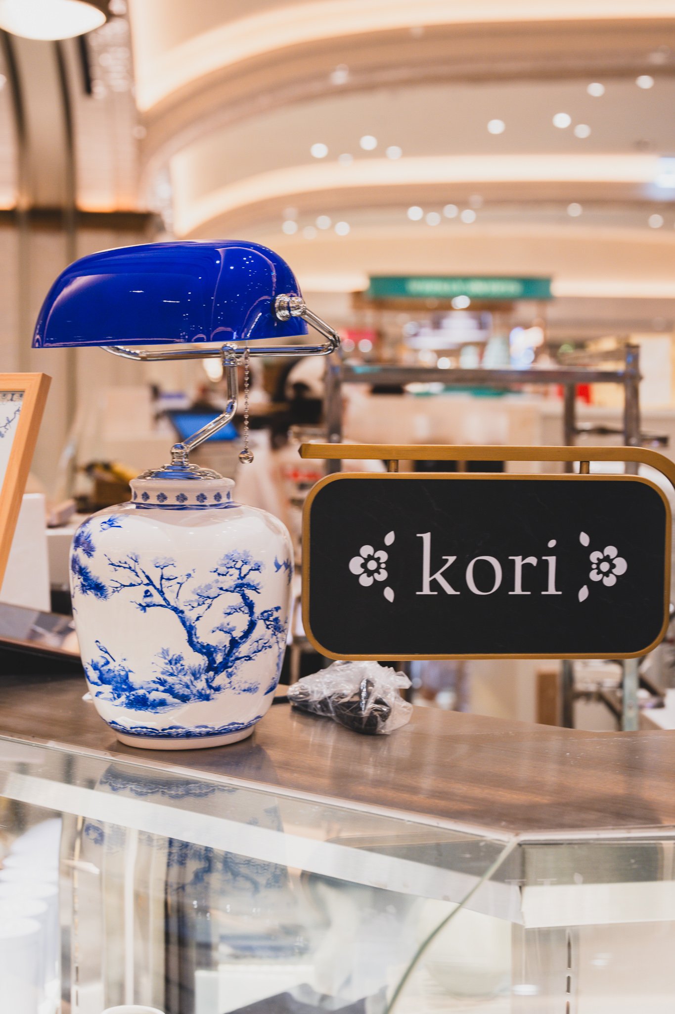 Blue banker's lamp and white porcelain jar next to the kori sign