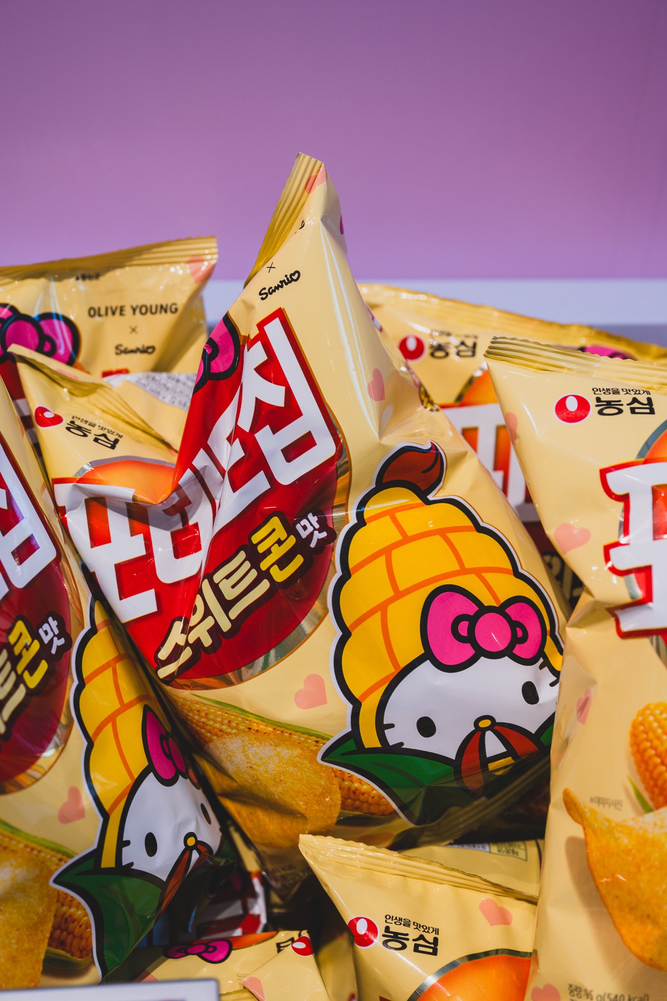 Nongshim's corn-flavored Kkokkalcorn snack in Hello Kitty-branded packaging, stacked in a display bin