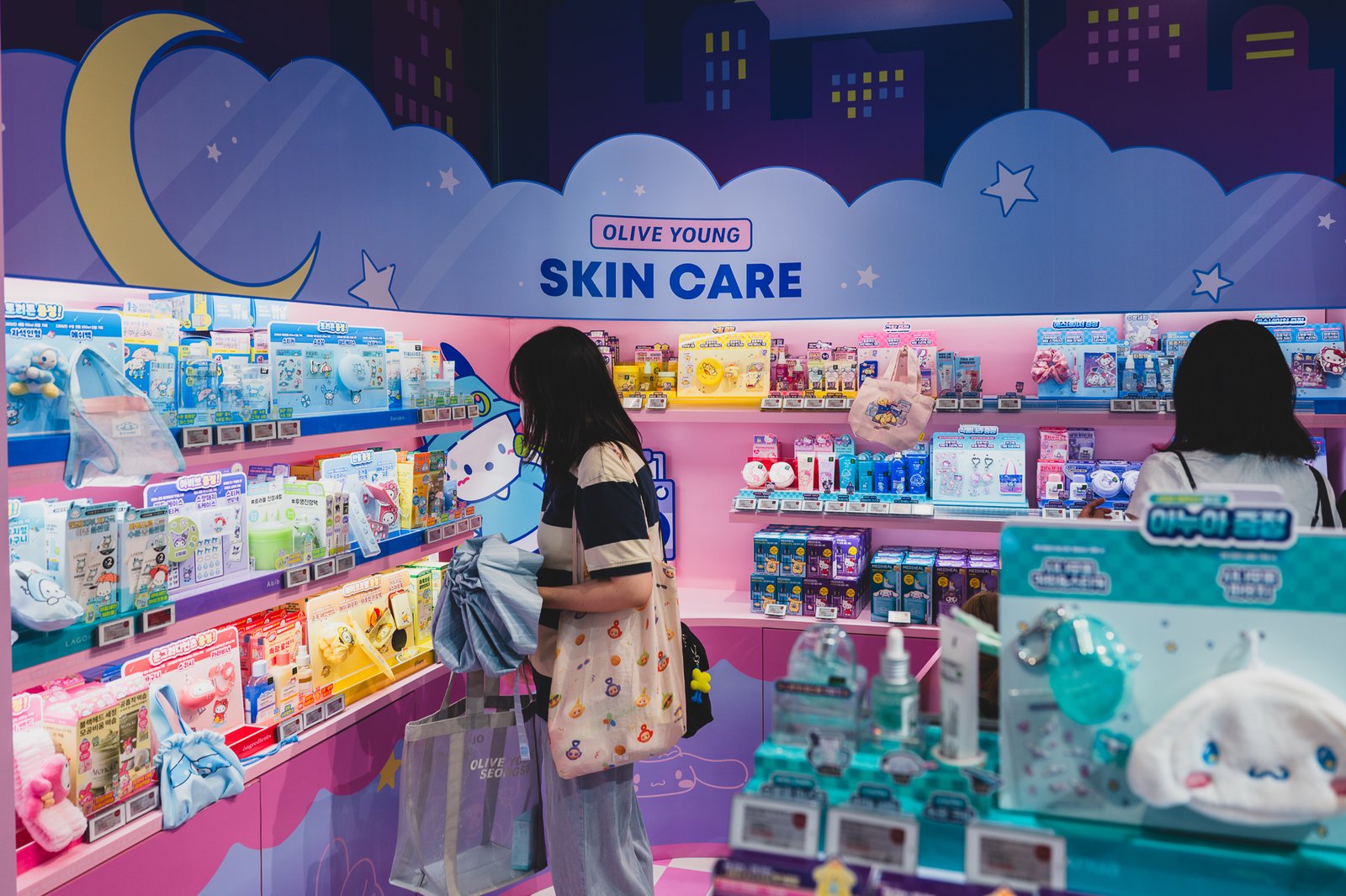 Interior of the skincare section with pink Sanrio-branded shelving, a shark-shaped display, and shoppers browsing crowded aisles