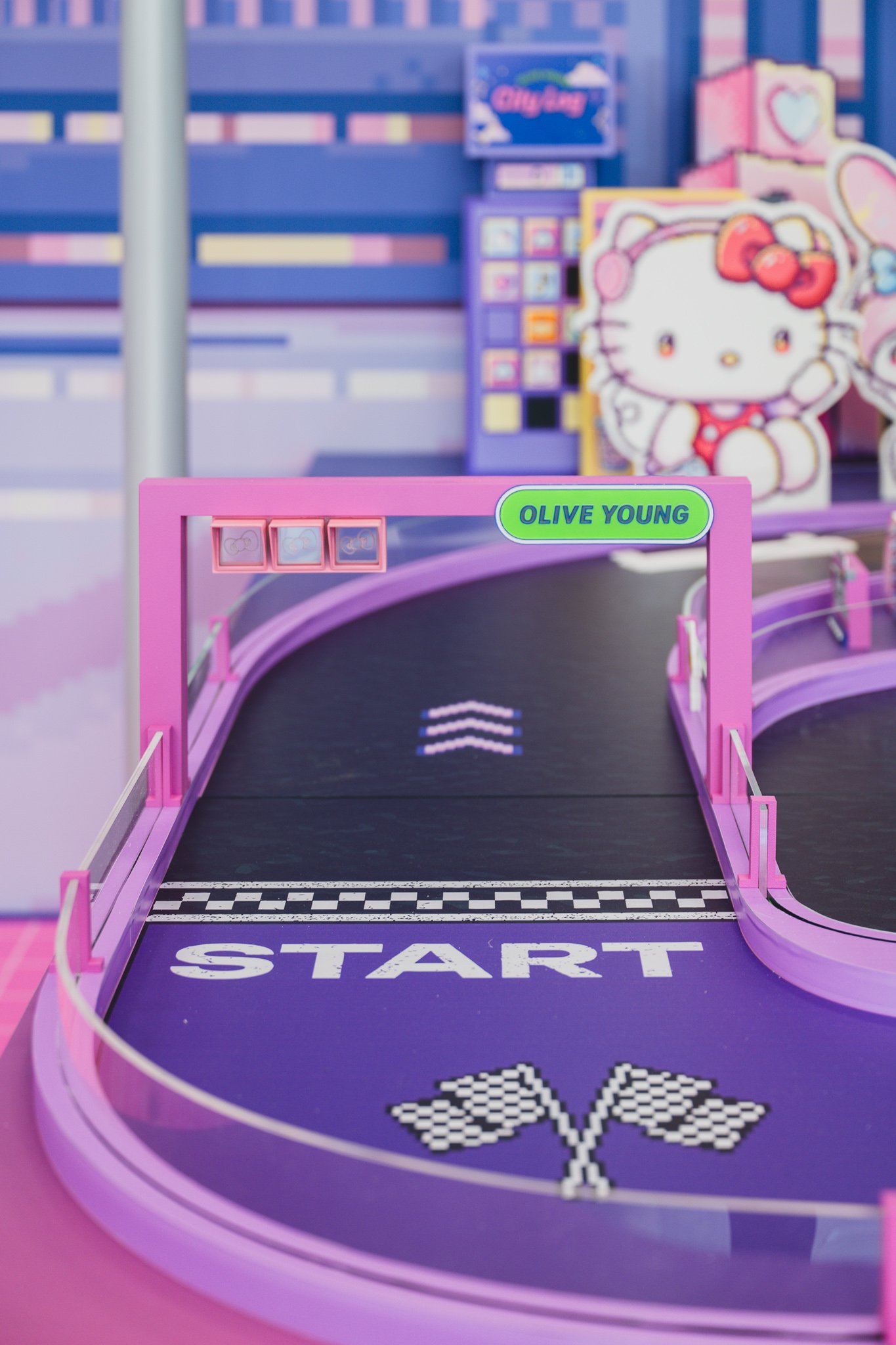A small racing-game track set into the floor of the experience zone, marked with a "START" line and Olive Young branding