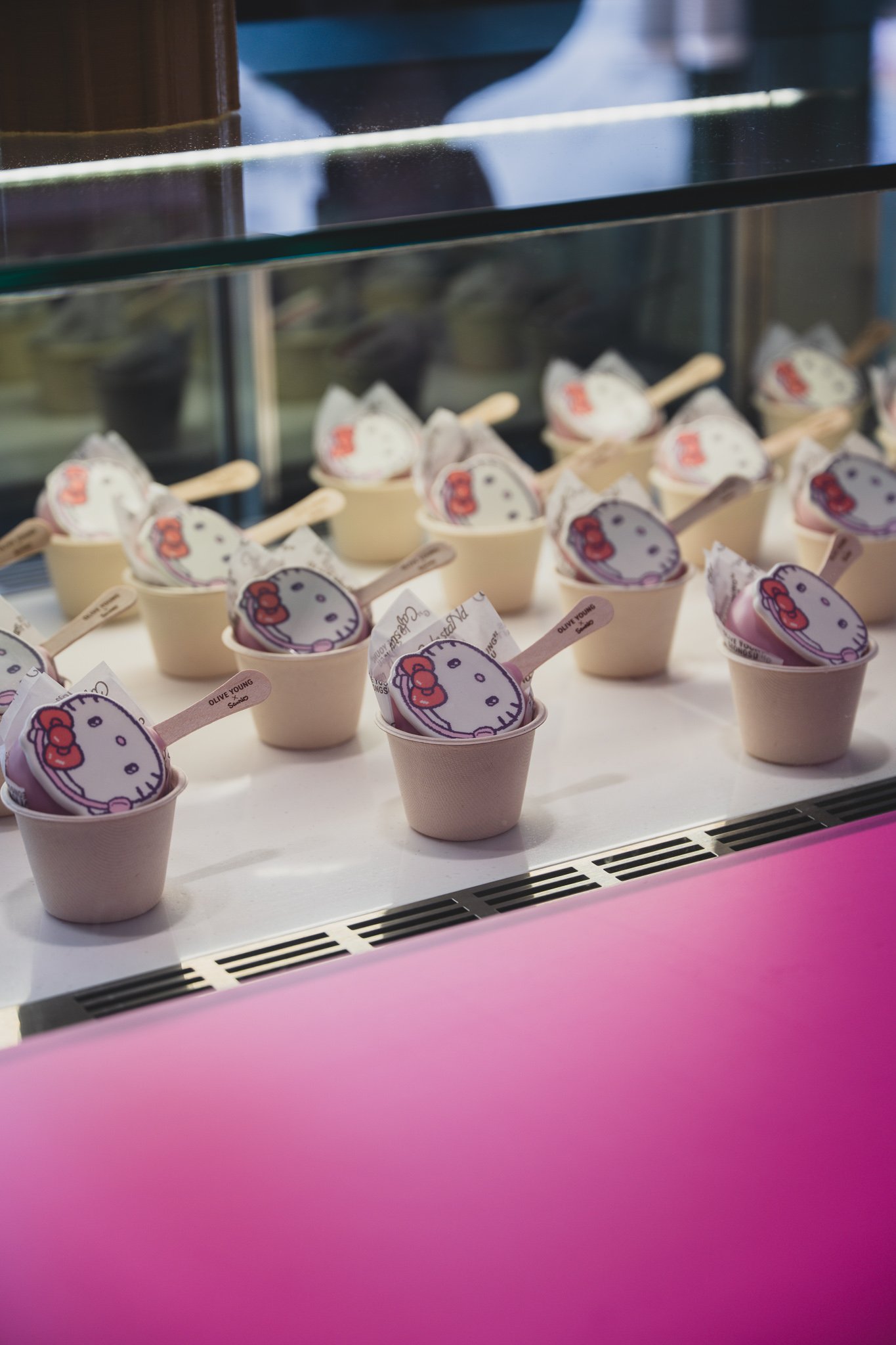 Counter of the CafestaNd café inside the pop-up, with a Sanrio character illustration menu board and rows of Hello Kitty-shaped cake pops in a display case