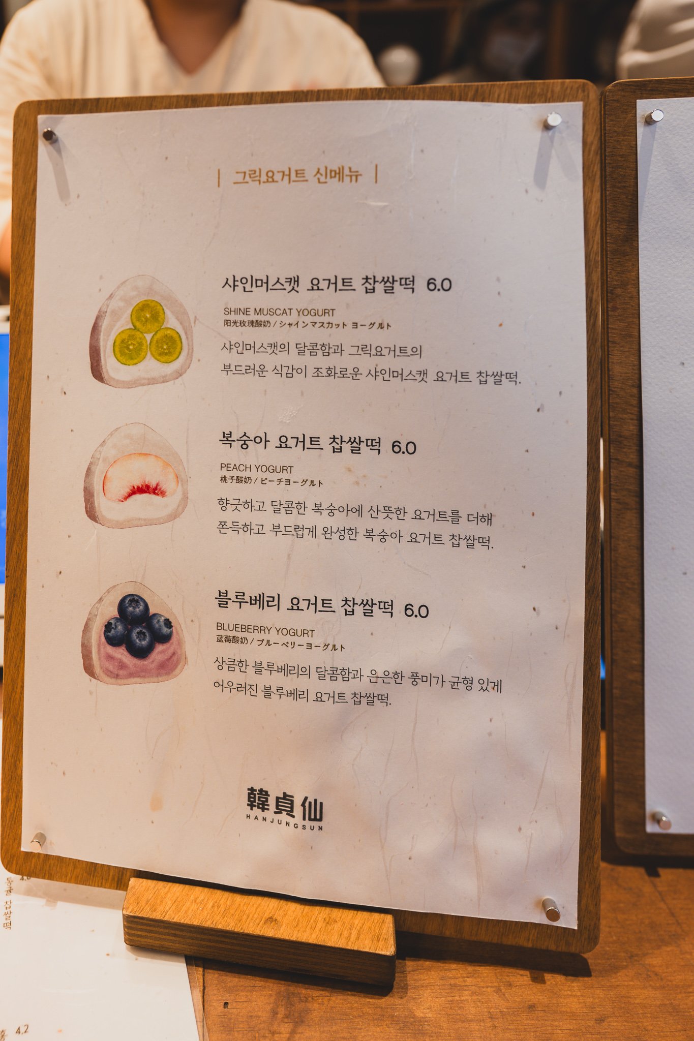 Seasonal Greek yogurt menu sign showing shine muscat, peach, and blueberry yogurt mochi