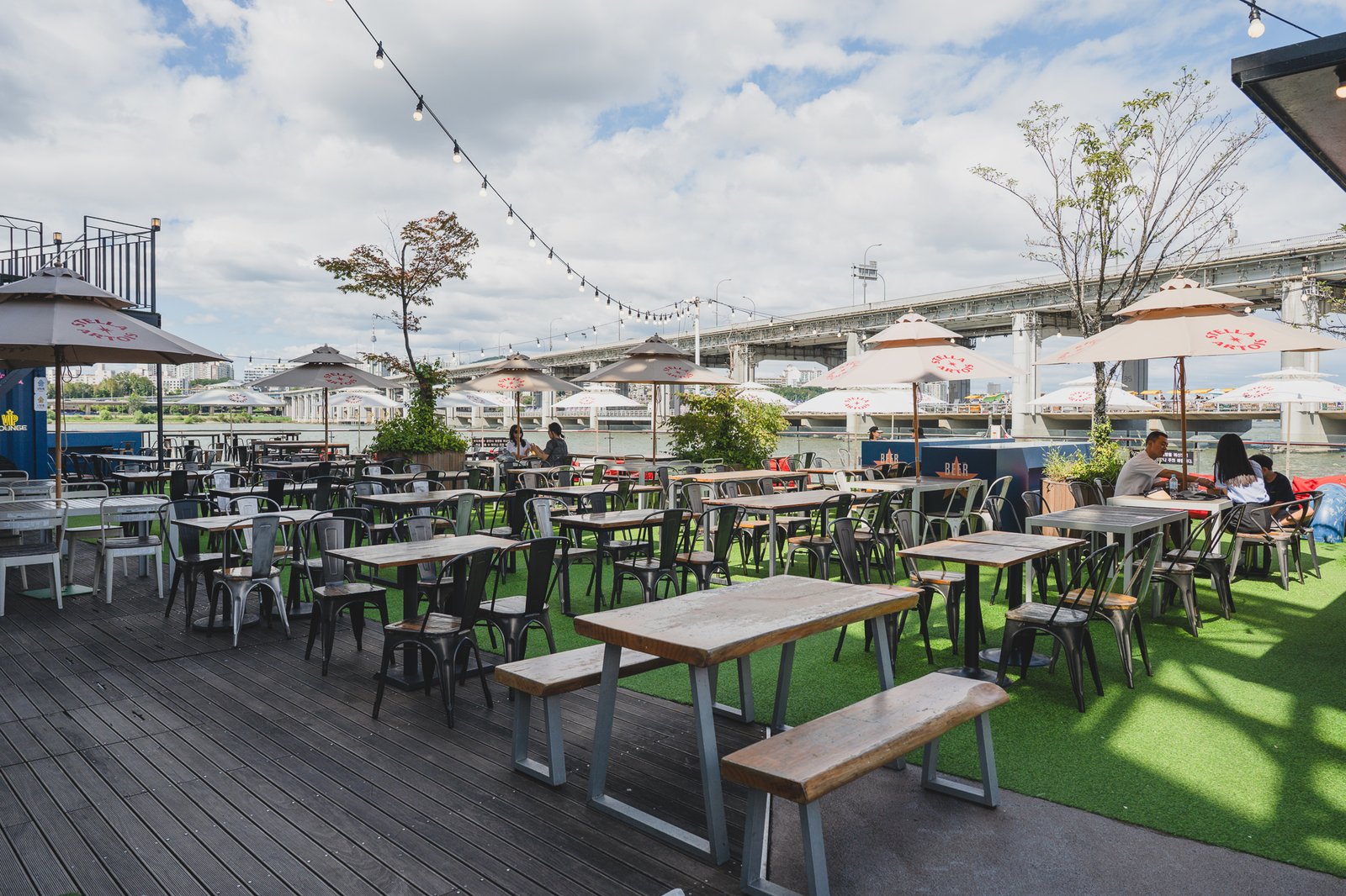 Terrace seating on artificial turf with steel tables and wood benches