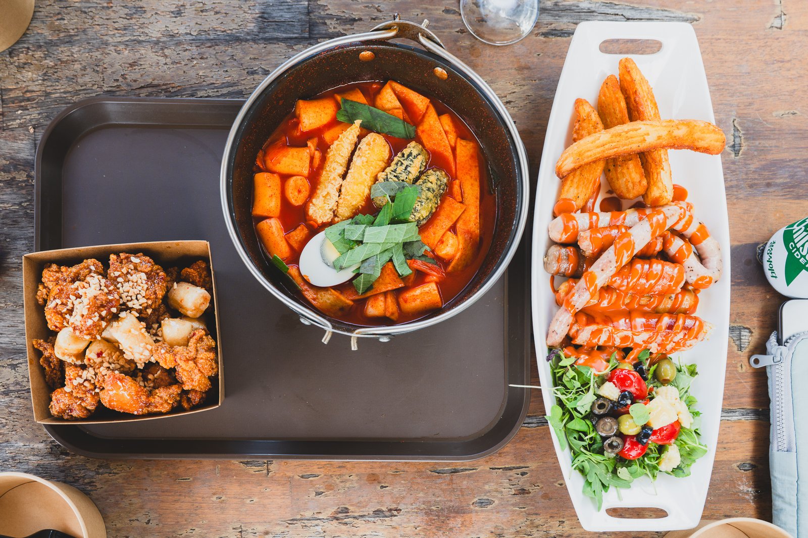 Full table shot with dakgangjeong, odeng-tang, and the sausage-and-wedge-fries platter together