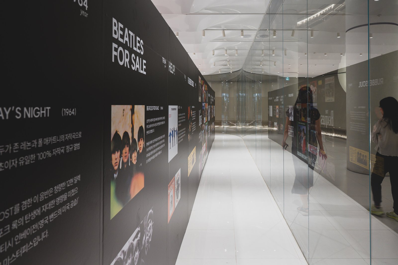 Hallway of year-by-year album displays along a reflective glass wall