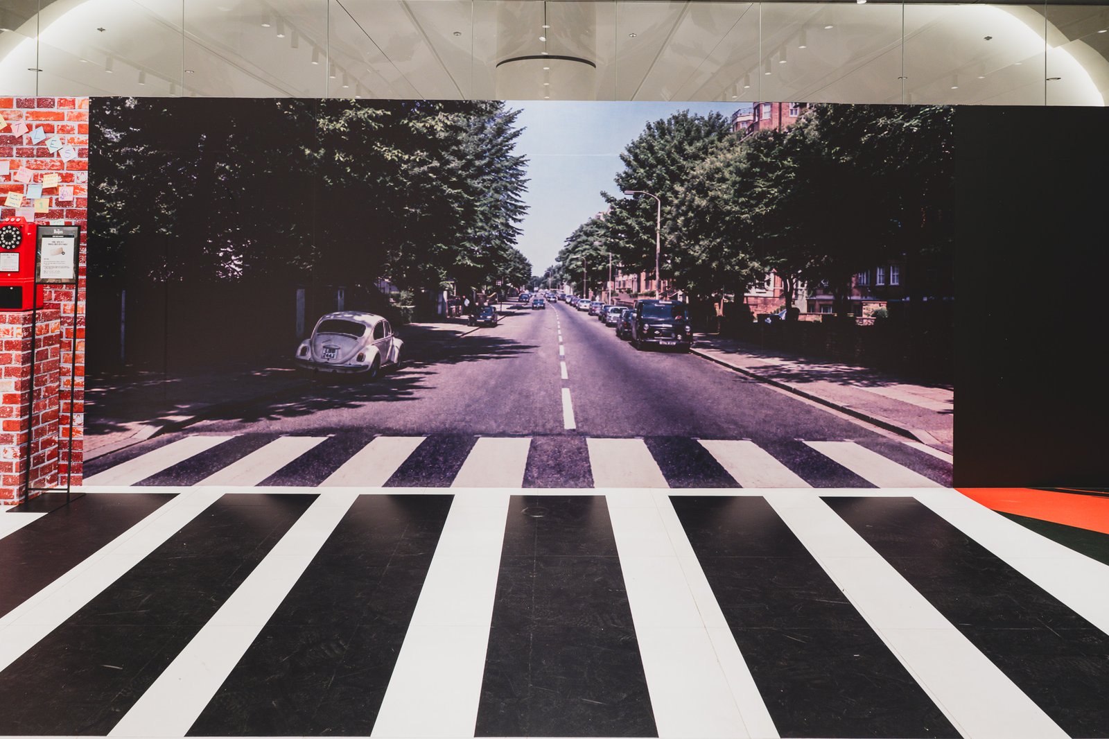 Full-size Abbey Road crosswalk replica with a red phone booth and a wall of Post-it notes