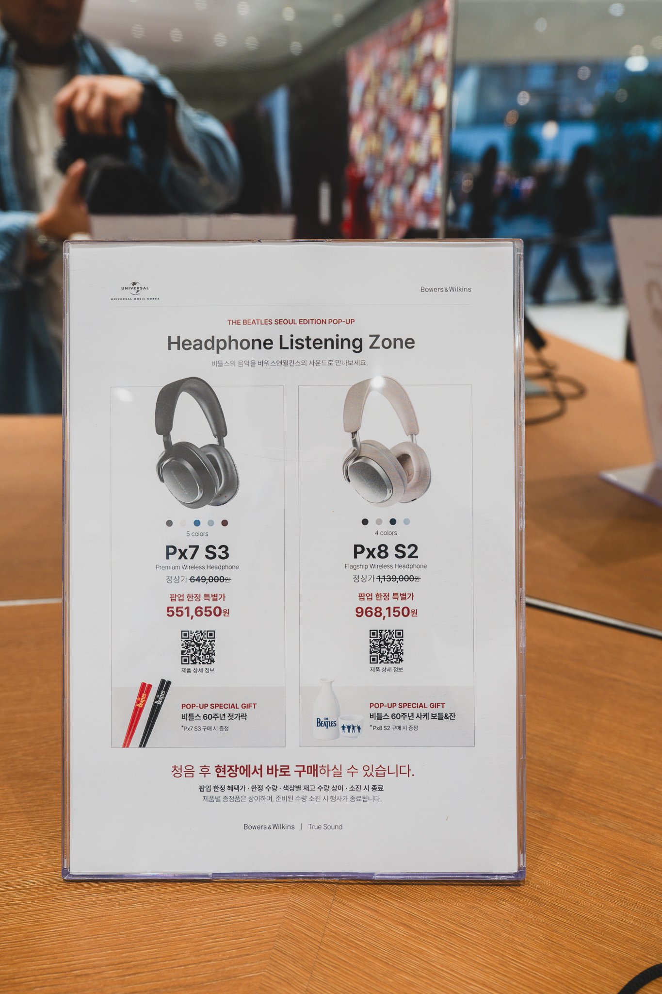 Pricing sign for the Headphone Listening Zone: Px7 S3 pop-up price 551,650 KRW, Px8 S2 pop-up price 968,150 KRW, with a free Beatles 60th anniversary gift with purchase