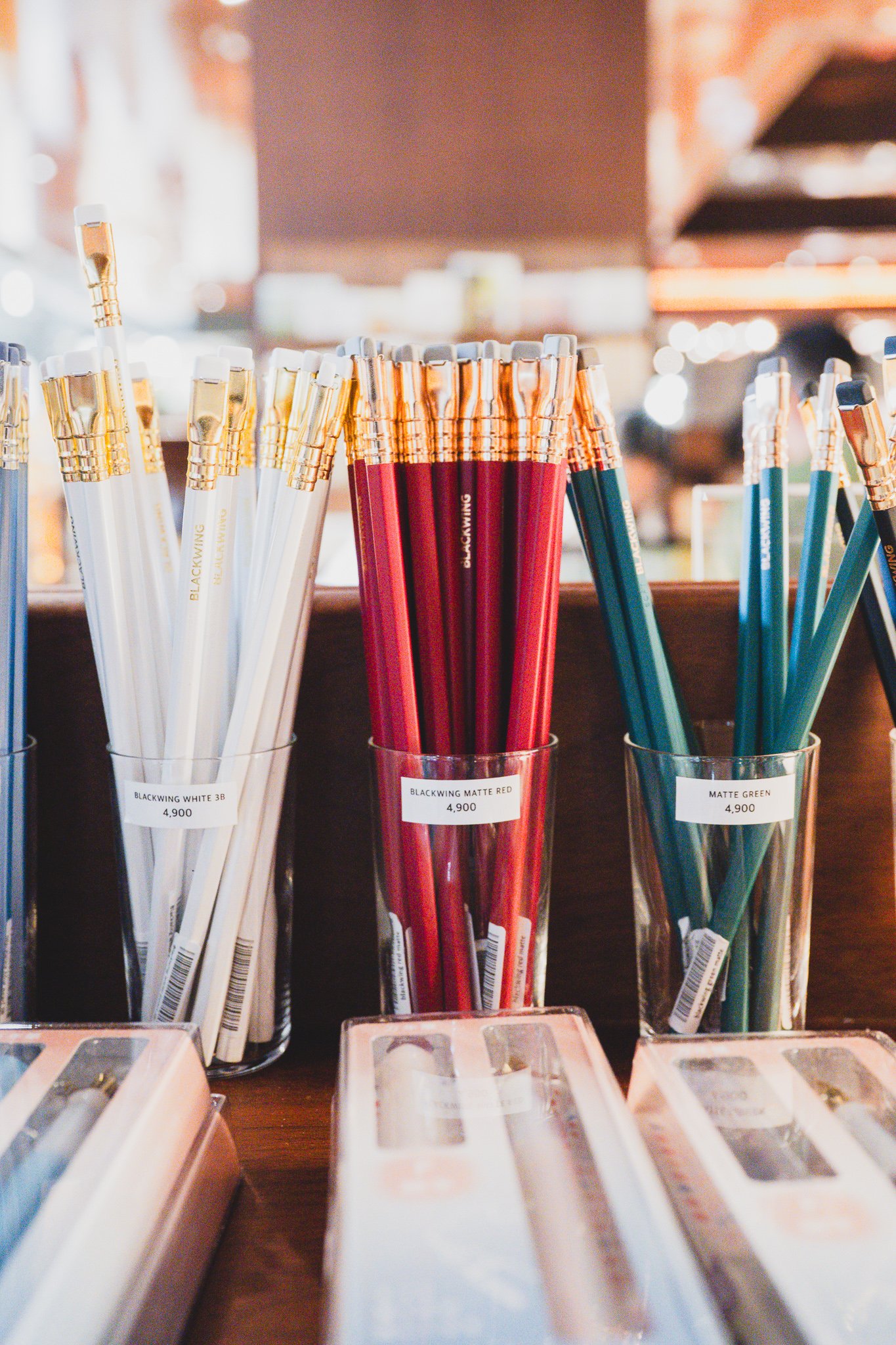 Blackwing pencils in white, matte red, and matte green, displayed standing in a glass cup