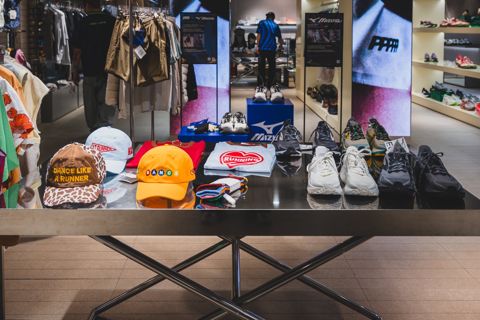 Caps, t-shirts, and socks displayed on a table, with a Mizuno store visible in the background