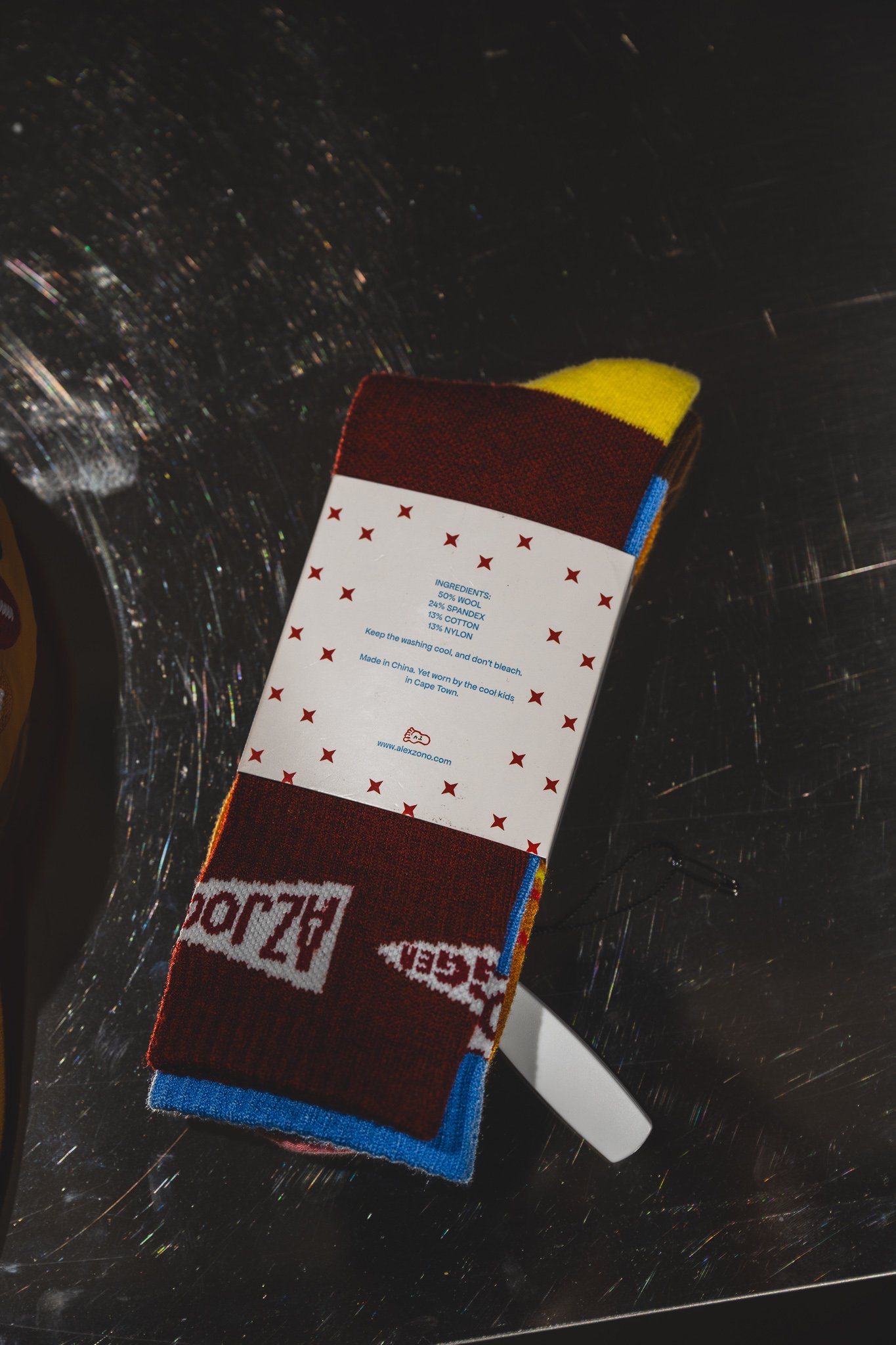 Sock packaging with a "50% WOOL, 24% SPANDEX" tag and the alexzono.com logo