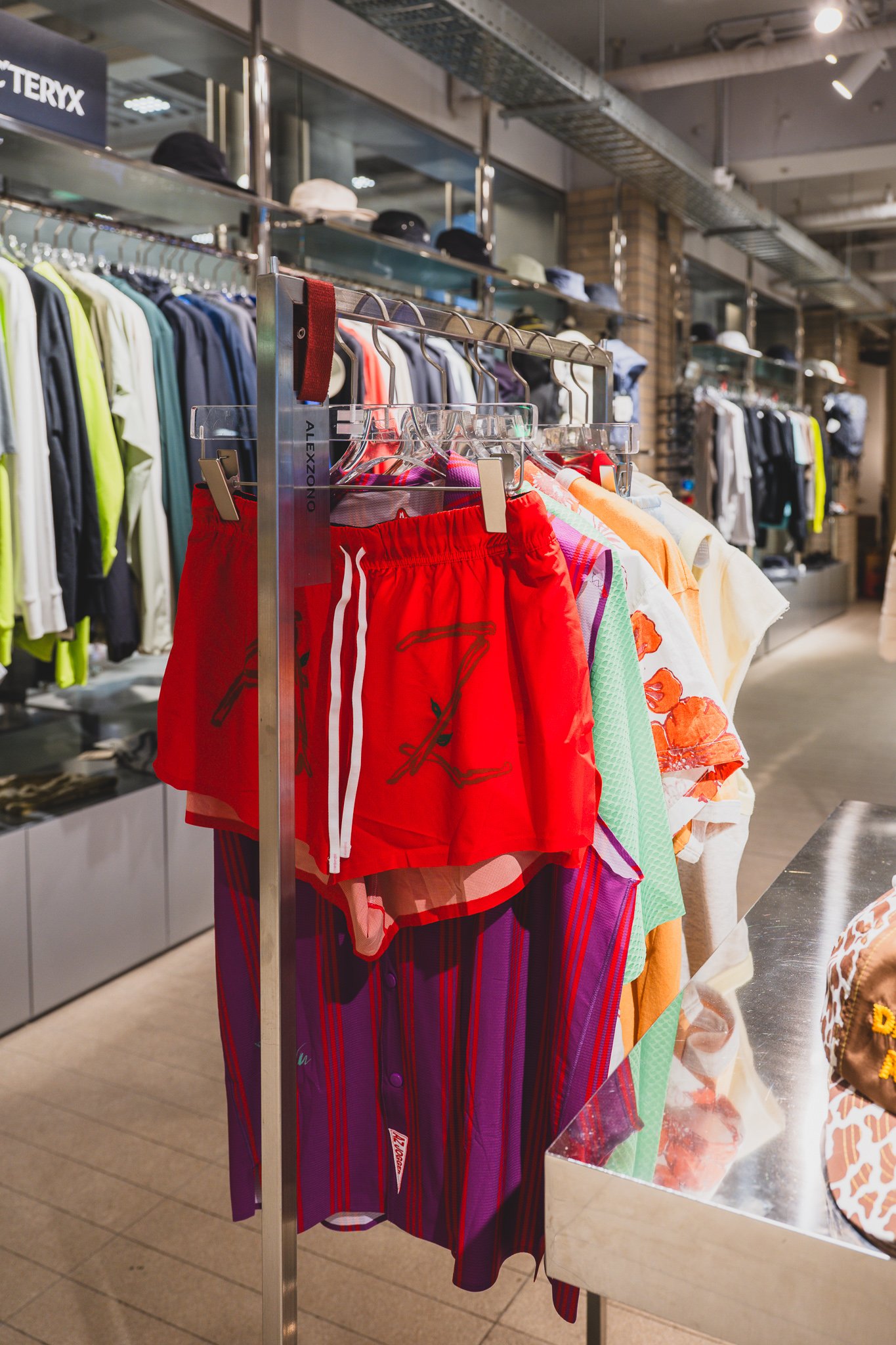Alex Zono apparel rack with red shorts and a purple-striped long skirt