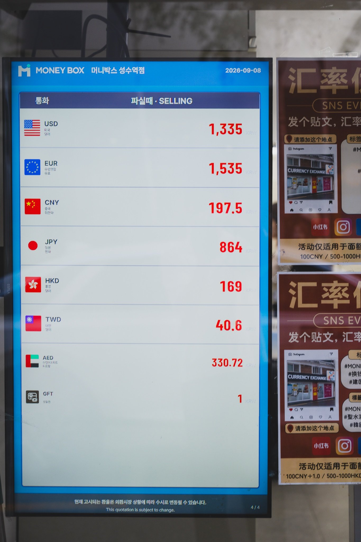 An electronic currency exchange rate board dated 2026-09-08 under the heading "파실때 · SELLING," listing USD 1,335, EUR 1,535, CNY 197.5, JPY 864, HKD 169, TWD 40.6 and AED 330.72 in red digits
