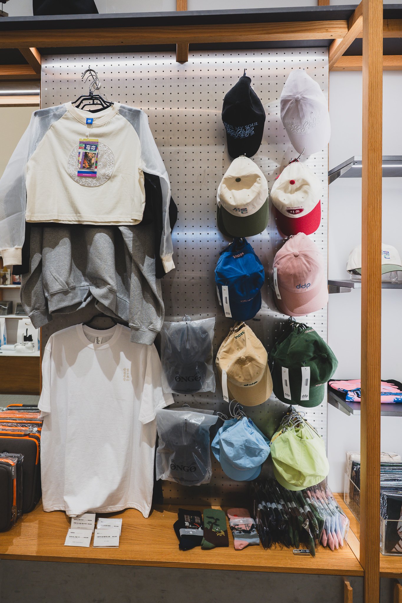 Rack of SEOUL MY SOUL embroidered caps in multiple colors, next to DDP-branded caps