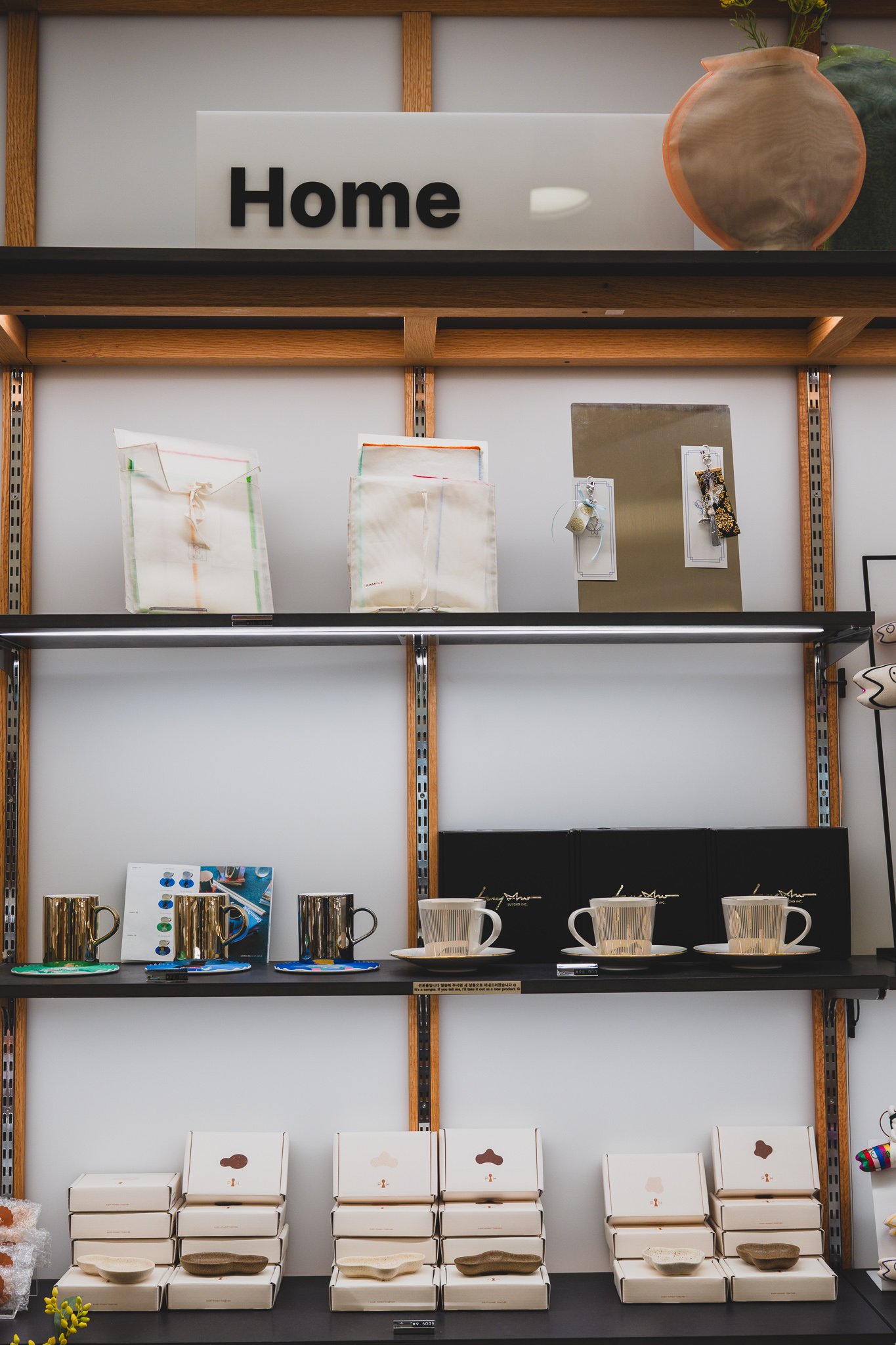 Home goods shelf with gold mugs and boxed traditional-pattern teacup sets