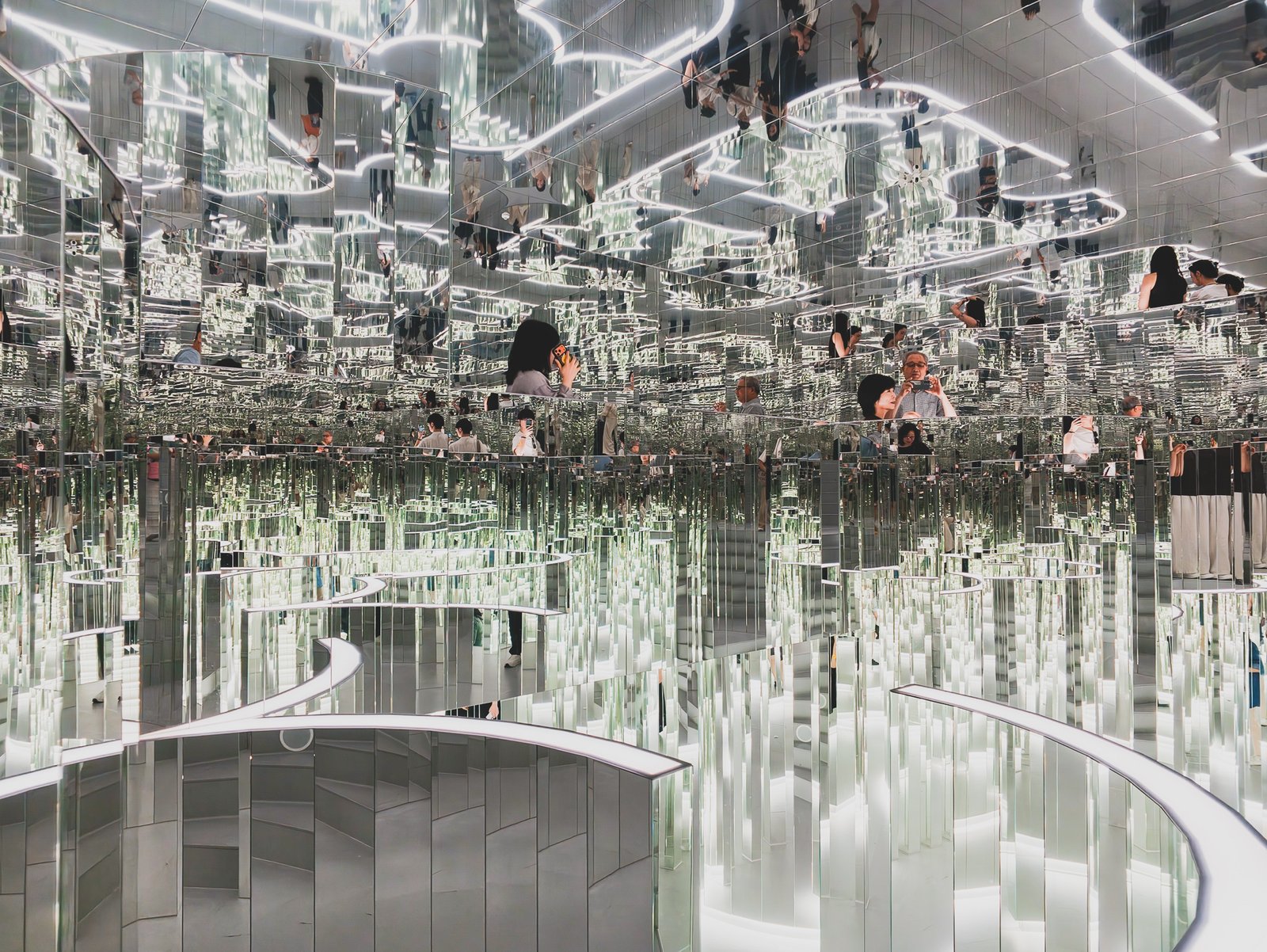 Mirrored ceiling reflecting curved neon lines in a wave-like pattern