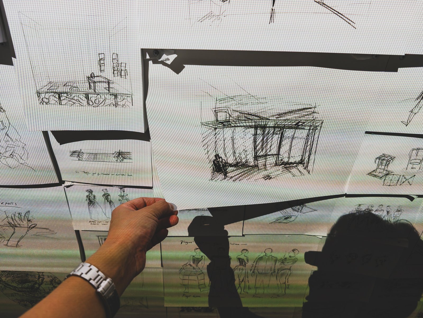 Visitor's hand pulling a single sketch page off the wall to take home