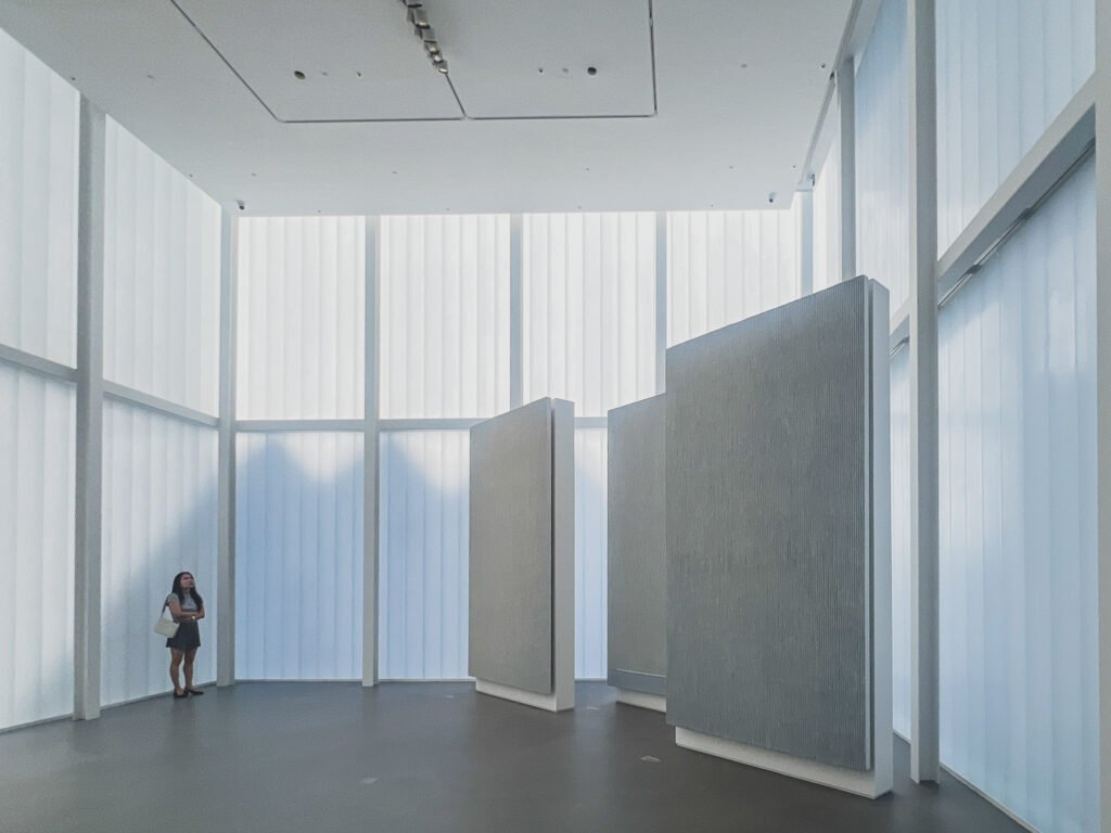 A visitor looks up inside the third-floor Cube, freestanding white hanji panels lit by the translucent ribbed walls