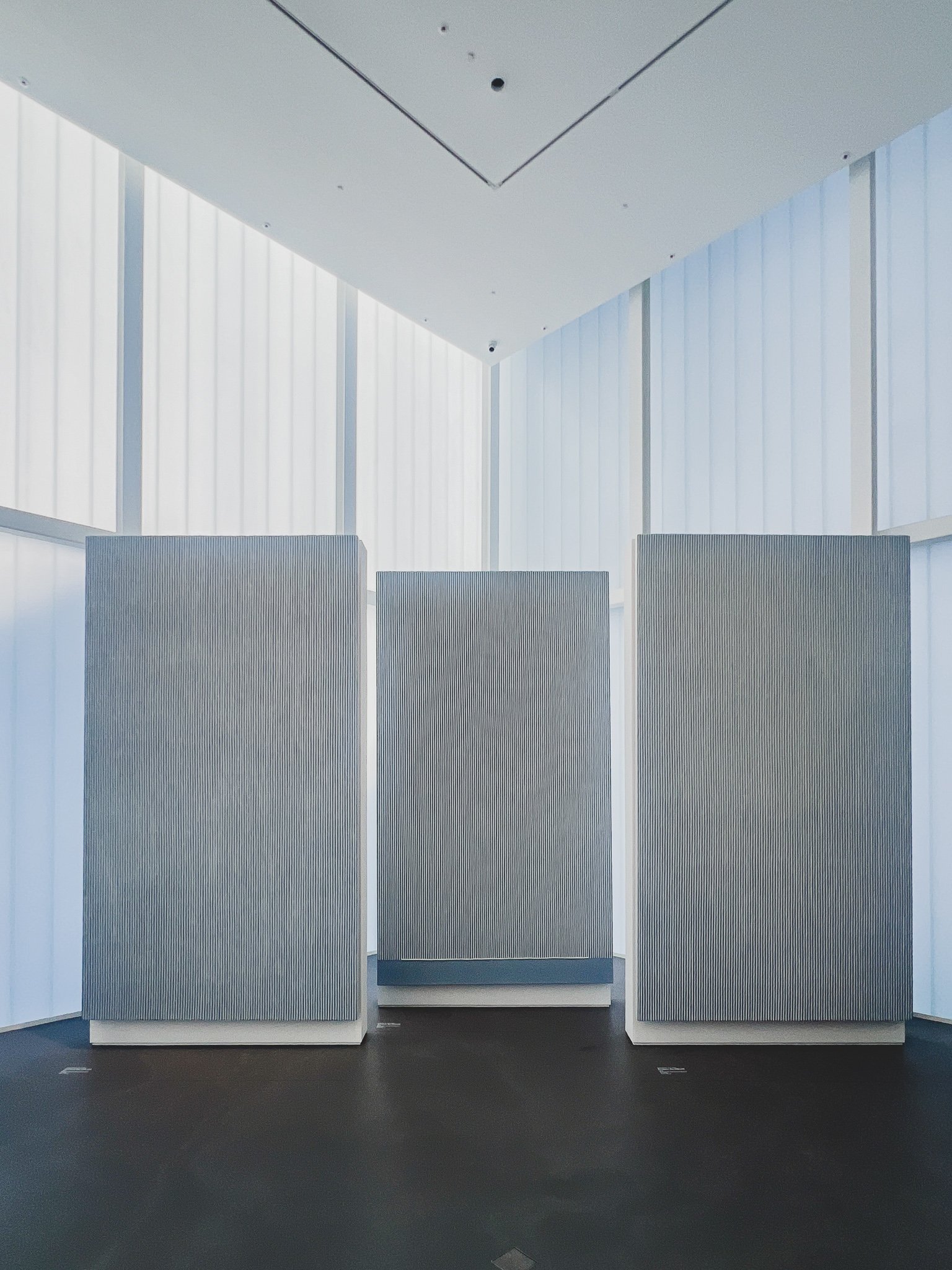 Third-floor cube-shaped gallery, translucent ribbed walls letting in soft natural light, large white hanji works standing as freestanding panels