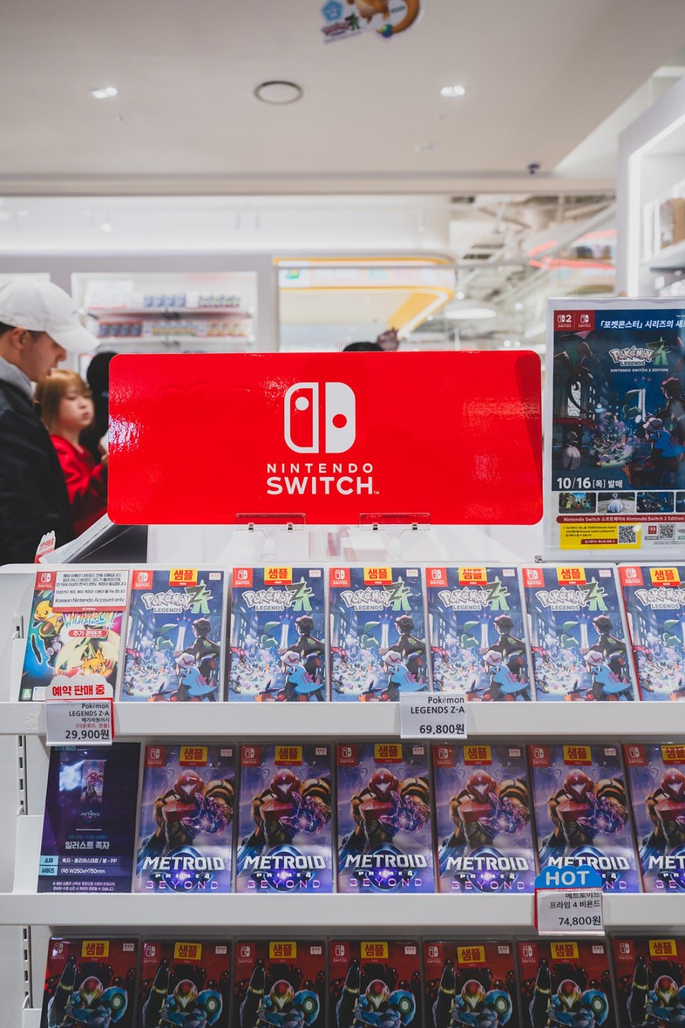 A red Nintendo Switch sign above shelves of physical game cases including Pokémon Legends Z-A and Metroid Prime 4