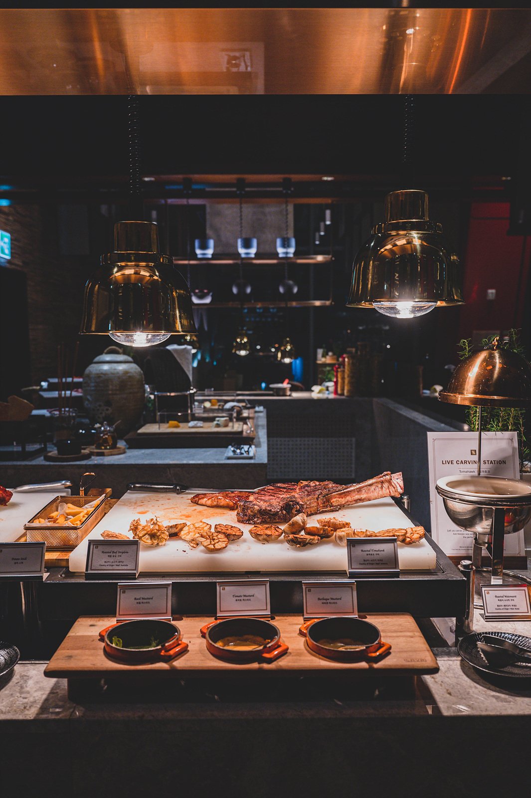 The live carving station at Spectrum, the buffet restaurant at Fairmont Ambassador Seoul, with copper pendant lighting over the open kitchen