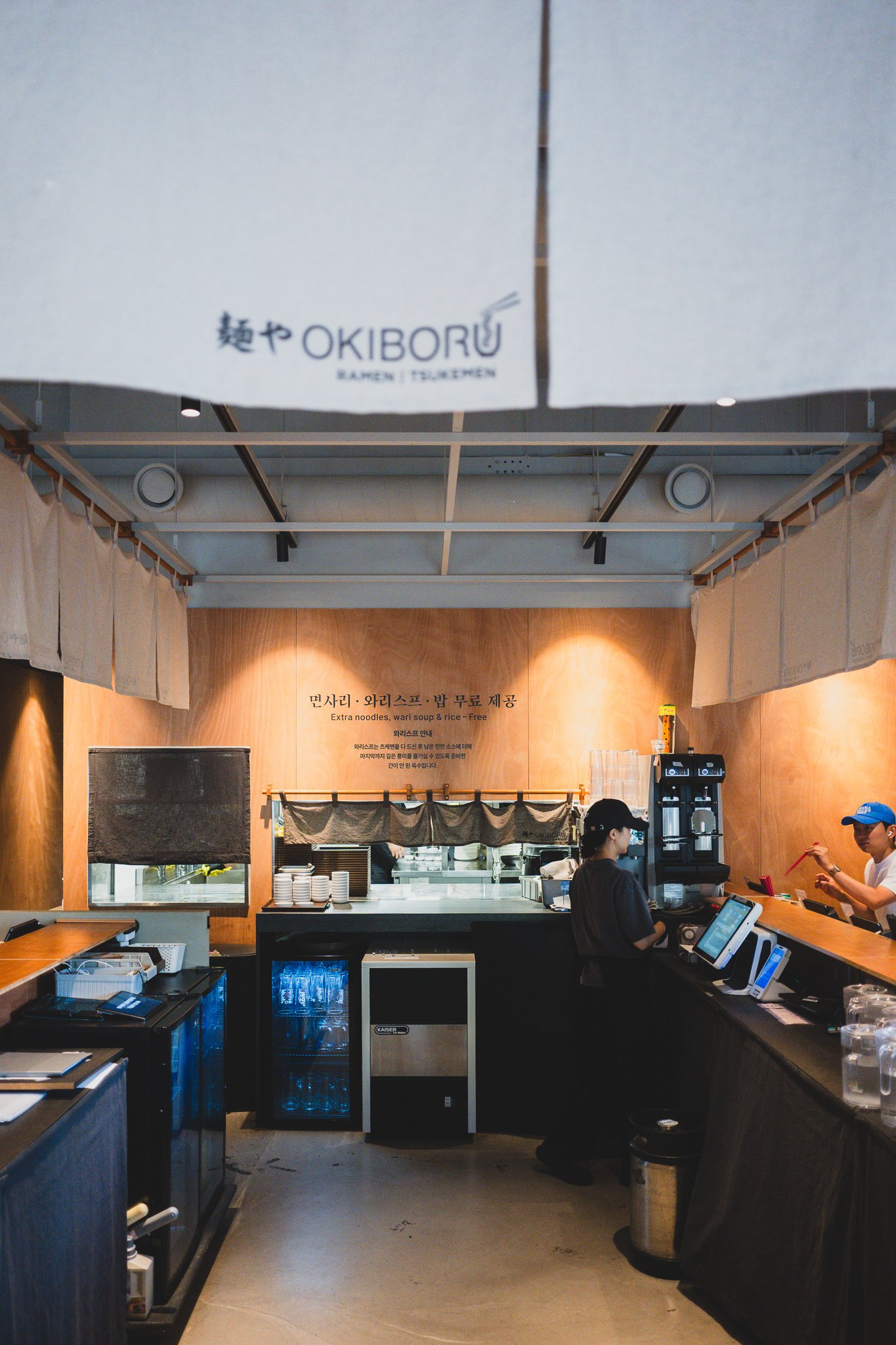 Open kitchen counter where noodles are being cooked and toppings added
