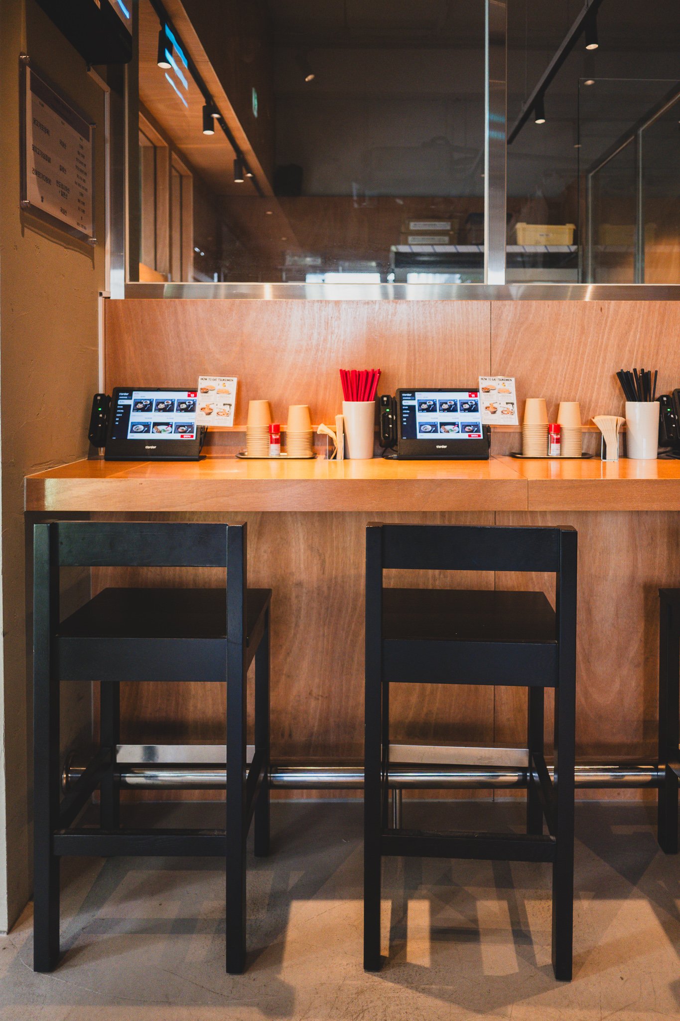 Row of single-seat bar counters, each with its own kiosk and black stool