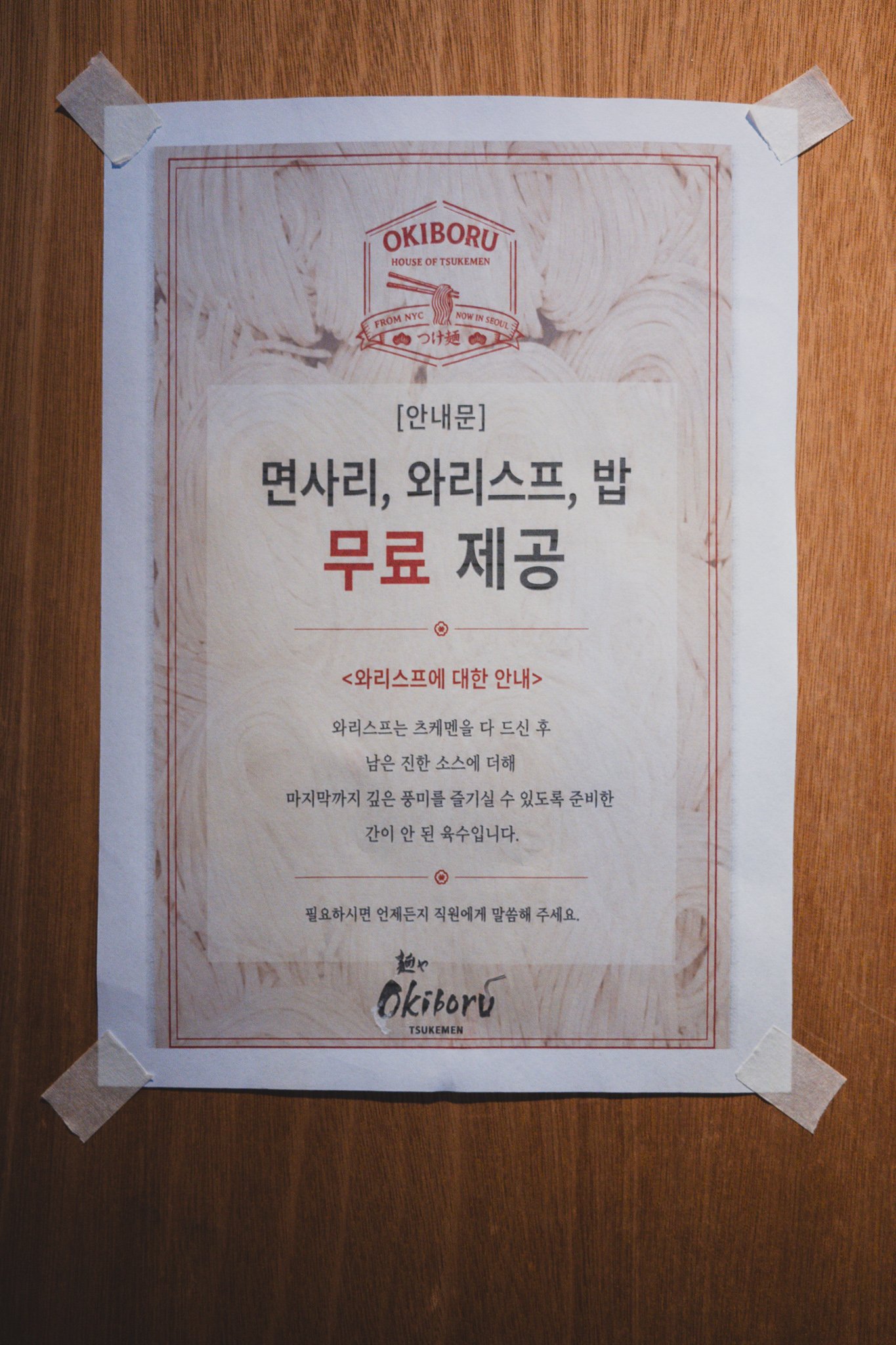 Sign reading "Extra noodles, wari soup & rice — free" above the kitchen