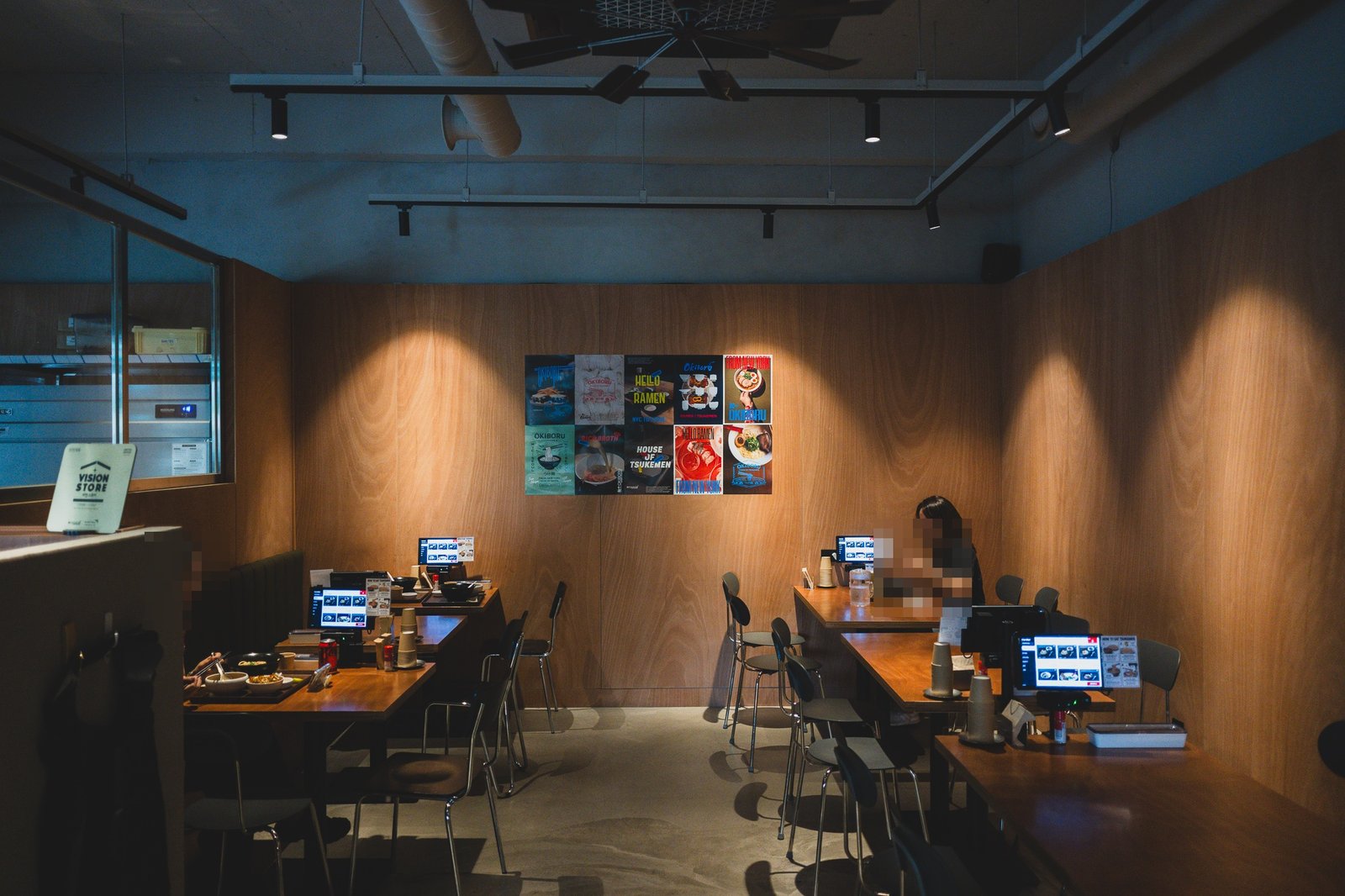 Dining room with wood box-style tables, kiosks at each seat, and other diners eating