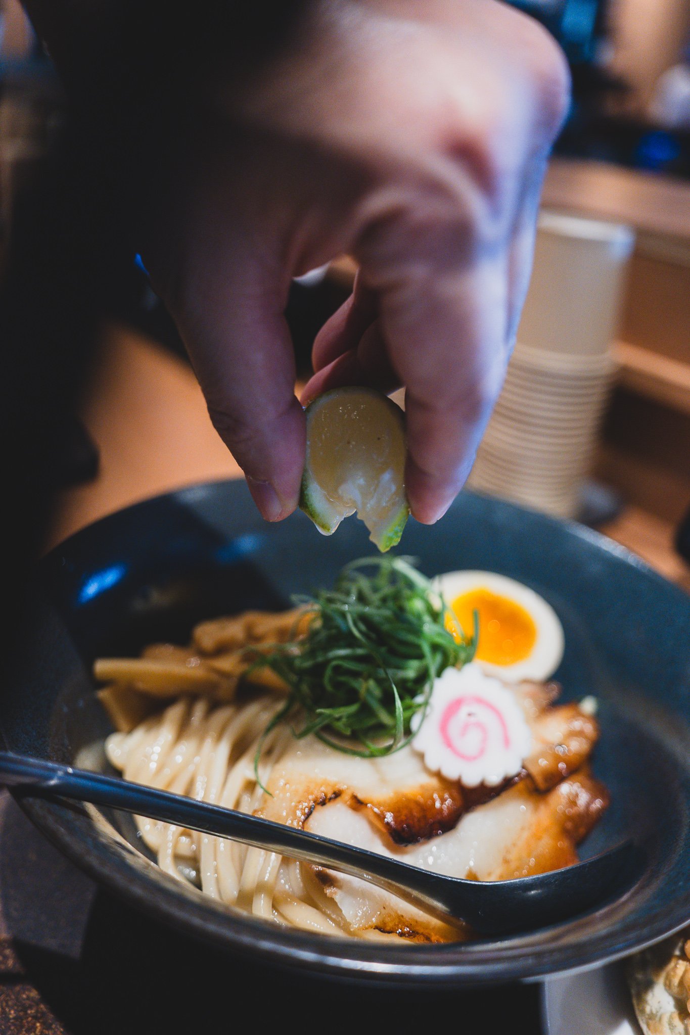 Squeezing a lime wedge over the noodles before eating