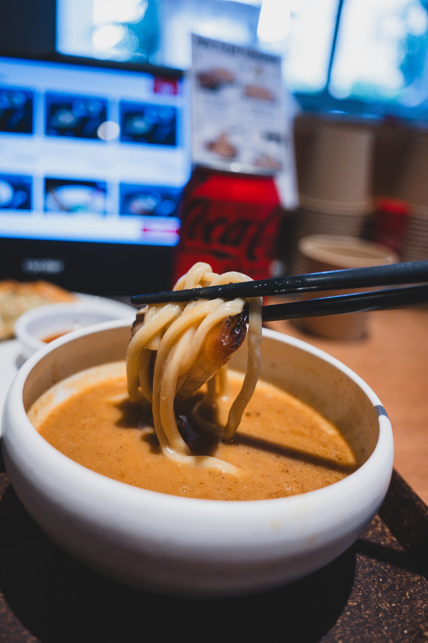 Lifting noodles topped with a thick slice of chashu