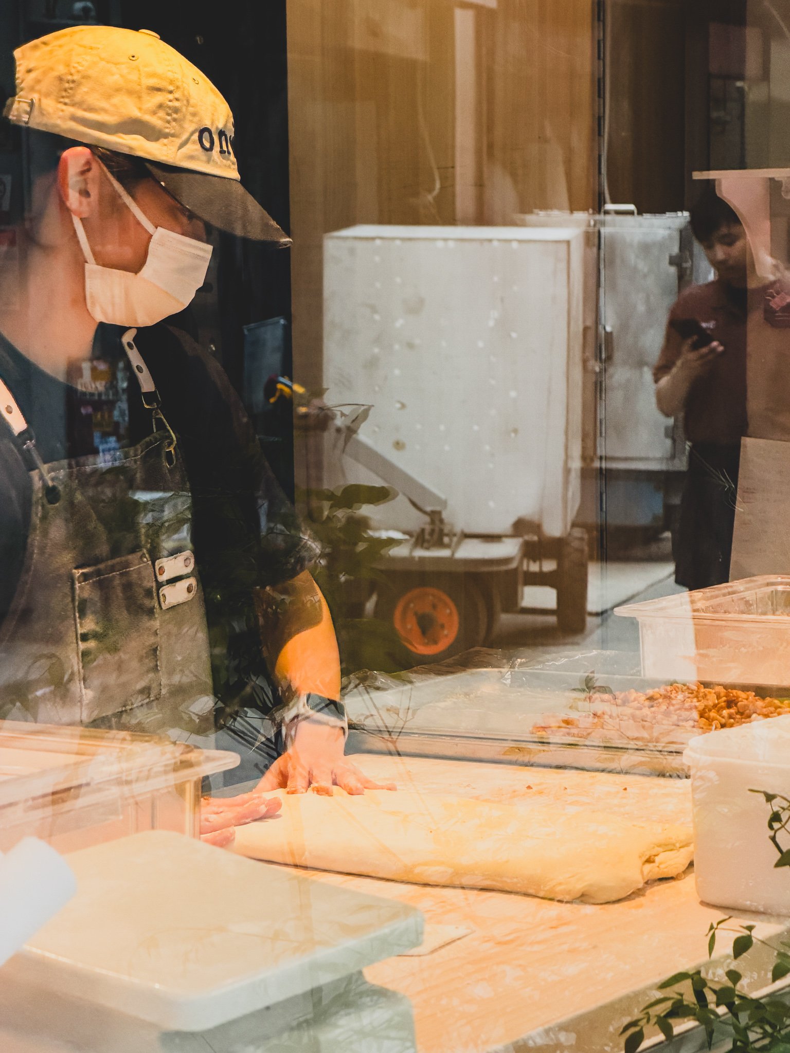 Bakery staff kneading dough visible through the street-facing window